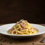 Final presentation of Classic Spaghetti Carbonara, a delicious gourmet plate of creamy pasta ready to be enjoyed on a rustic table.
