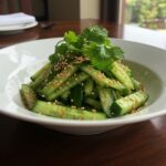 Final presentation of Din Tai Fung style Cucumber Salad, featuring crispy cucumbers garnished with sesame seeds, ready to serve in an elegant bowl.