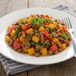 Delicious Easy Mediterranean Ground Beef Stir Fry plated beautifully with colorful vegetables and ground beef on a wooden table, garnished with parsley, showcasing a perfect meal.