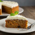 Delicious slice of Easy Oatmeal Carrot Cake with cream cheese frosting, beautifully presented on a rustic table.