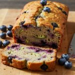 Freshly baked blueberry zucchini bread displayed on a cutting board, highlighting its moist crumb and scrumptious blueberries.