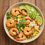 Final presentation of a grilled shrimp bowl with avocado, corn salsa, and creamy garlic sauce, perfect for a fresh and healthy meal.