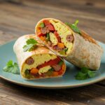 A delicious high protein breakfast burrito cut in half, showcasing nutritious filling on a rustic wooden table.