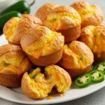 Delicious jalapeño cheddar popovers served on a platter, showcasing their golden color and cheesy texture, ideal for a savory snack.