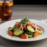 Final presentation of marinated cucumbers, onions, and tomatoes served on a plate; a vibrant and healthy salad dish.