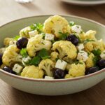 Delicious Mediterranean marinated cauliflower salad served in a bowl with colorful vegetables and herbs.