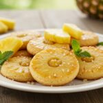 Delicious pineapple upside sugar cookies display on a plate, garnished with fresh pineapple slices and mint, perfect for a dessert spread.