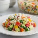 A vibrant and appetizing close-up of Rainbow Orzo Salad served on a white plate, perfect for a healthy meal.