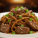 Final presentation of Sticky Beef Noodles, garnished with sesame seeds and green onions, highlighting the delicious sticky sauce and vibrant colors.