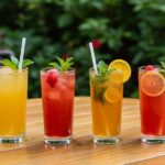 a selection of summer detox drinks in vibrant colors, elegantly presented on a table with a fresh garden ambiance