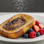 Deliciously presented Best Crème Brûlée French Toast with berries, featuring a golden caramelized sugar crust, perfect for breakfast.