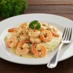Delicious creamy garlic shrimp served over silky mashed potatoes, an inviting dish perfect for seafood lovers, elegantly plated and garnished.