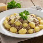 Final presentation of creamy ground beef gnocchi, showing a delicious and creamy dish garnished with parsley and cheese.
