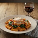 Final presentation of delicious spinach tomato pasta garnished with Parmesan cheese, showcasing an inviting dining experience.