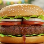 Delicious Easy Ground Beef Burger displayed in close-up, highlighting the juicy patty and fresh toppings in a backyard barbecue setting.