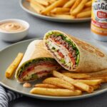 Final presentation of Homemade Big Mac Wraps sliced, showcasing layers of ingredients with fries, perfect for enjoying a tasty meal.