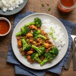 Final presentation of Honey Sriracha Ground Chicken and Broccoli, served with rice and dipping sauce, perfect for a family meal.
