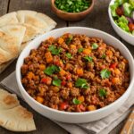 Final presentation of a delicious Mediterranean ground beef stir-fry recipe, garnished and ready to serve with pita bread and salad.