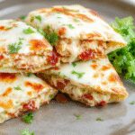 A close-up of a golden-brown quesadilla with melted cheese, crispy bacon pieces, and chunks of chicken visible through the slightly crispy, grilled exterior. The quesadilla is sliced into triangles and served on a rustic wooden plate, garnished with fresh cilantro and a side of sour cream and salsa. The melted cheese oozes slightly from the edges, showcasing a savory filling with a perfectly toasted crust.