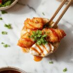 A vibrant bowl featuring crispy golden-brown Japanese katsu slices arranged neatly atop steamed rice, topped with shredded cabbage and drizzled with dark, glossy tonkatsu sauce. The bowl is presented on a rustic wooden table with chopsticks resting on the side, capturing a mouthwatering, crispy texture and colorful presentation.
