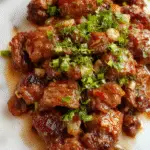 A vibrant plate of Chinese pepper steak hot off the skillet, featuring tender slices of beef coated in glossy, savory sauce, colorful bell peppers and onions, garnished with green onions, all arranged attractively on a white ceramic dish