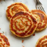 A stack of golden-brown German potato pancakes on a rustic white plate, garnished with fresh dill and a dollop of sour cream, with crispy edges and a tender interior visible.