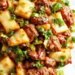 A vibrant stir fry dish in a black wok featuring shredded green cabbage, tender ground beef, sliced carrots, and chopped green onions, glazed with a glossy sauce. The dish is steaming hot, with colorful vegetables contrasting against the savory beef, and garnished with sesame seeds and fresh herbs.
