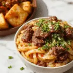 A steaming bowl of Mongolian Ground Beef Noodles featuring tender ground beef browned to a rich color, nestled atop a bed of perfectly cooked, glossy noodles. The dish is garnished with chopped green onions and sesame seeds, with a vibrant sauce coating the ingredients. The bowl is placed on a rustic wooden table, with chopsticks resting beside it, evoking an inviting Asian culinary presentation.