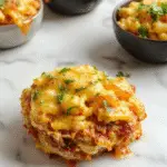 A creamy bowl of high protein macaroni and cheese featuring perfectly cooked elbow macaroni coated in a rich, cheesy sauce, topped with finely chopped herbs and slices of grilled chicken on the side, all served on a rustic wooden table with a sprig of parsley for garnish.