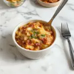A vibrant plate of taco pasta featuring seasoned ground beef, colorful bell peppers, and melted cheese atop a bed of pasta, garnished with fresh cilantro and sliced jalapenos in a rustic bowl.